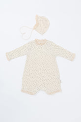 Front view of the Lumiere Bodysuit in Classic Blossom – a long-sleeve baby romper featuring lace trimming and a matching bonnet